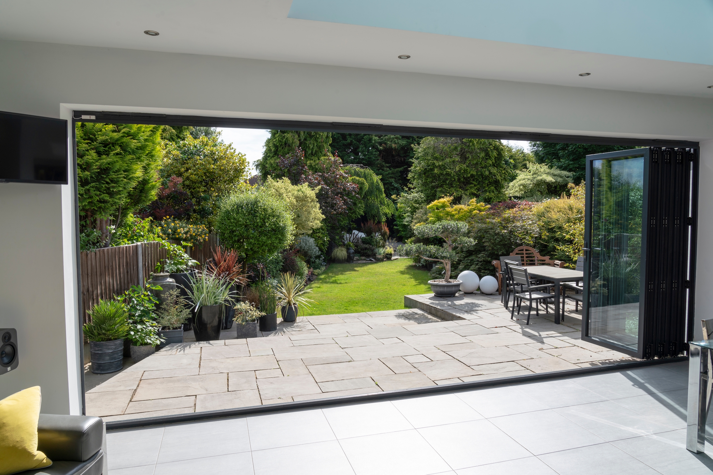 open sheerline bifold doors with garden, patio and lawn views.