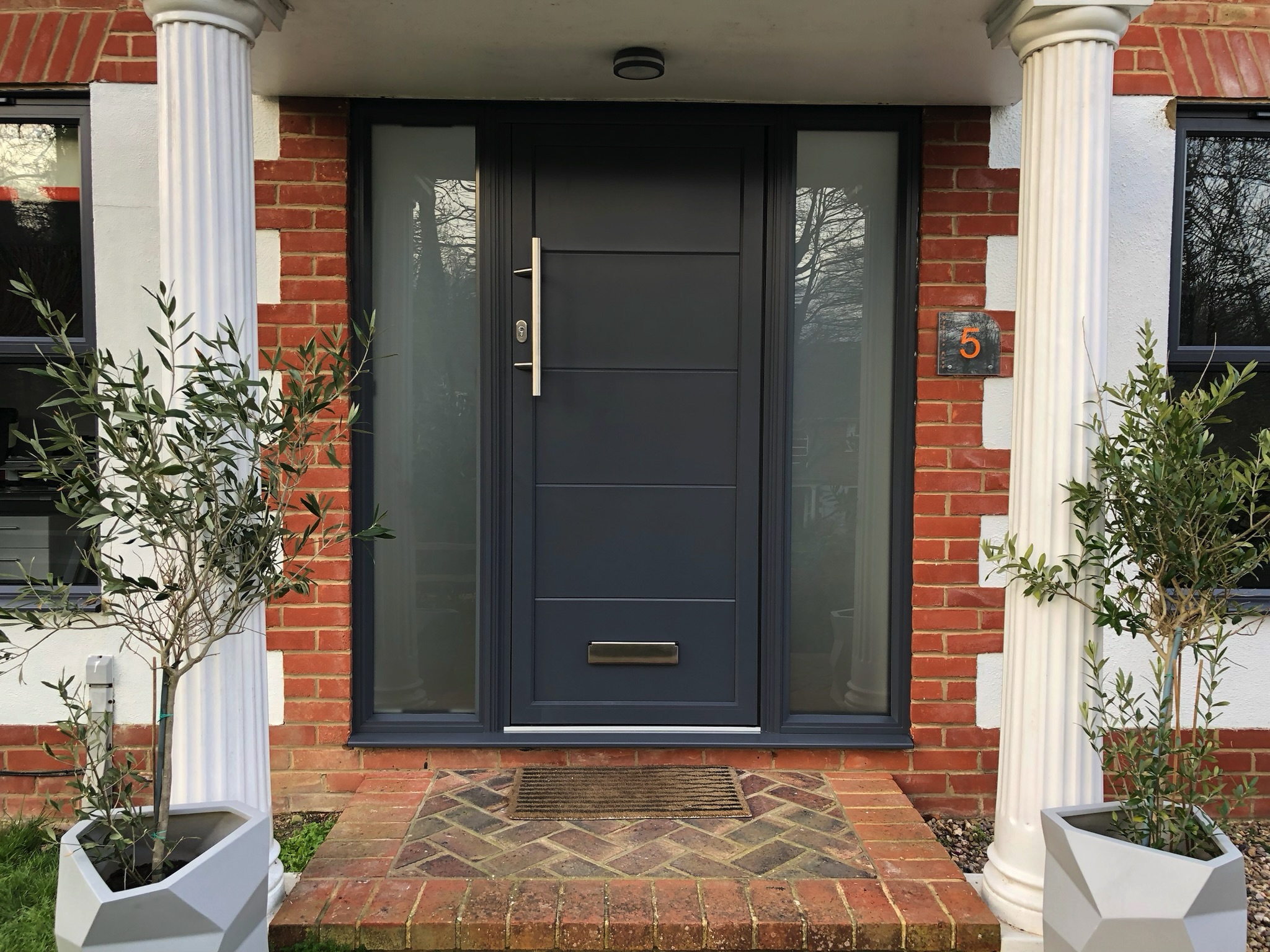 origin front door in a brick and render porch