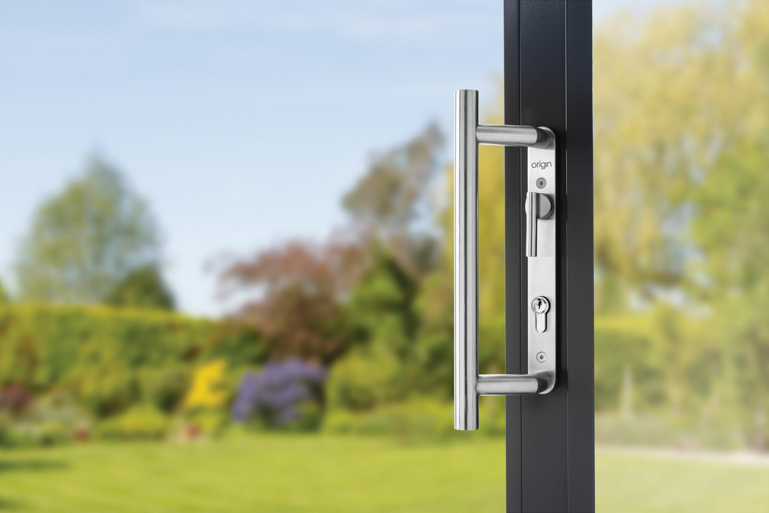 close up of origin sliding door handle with lawn and trees 