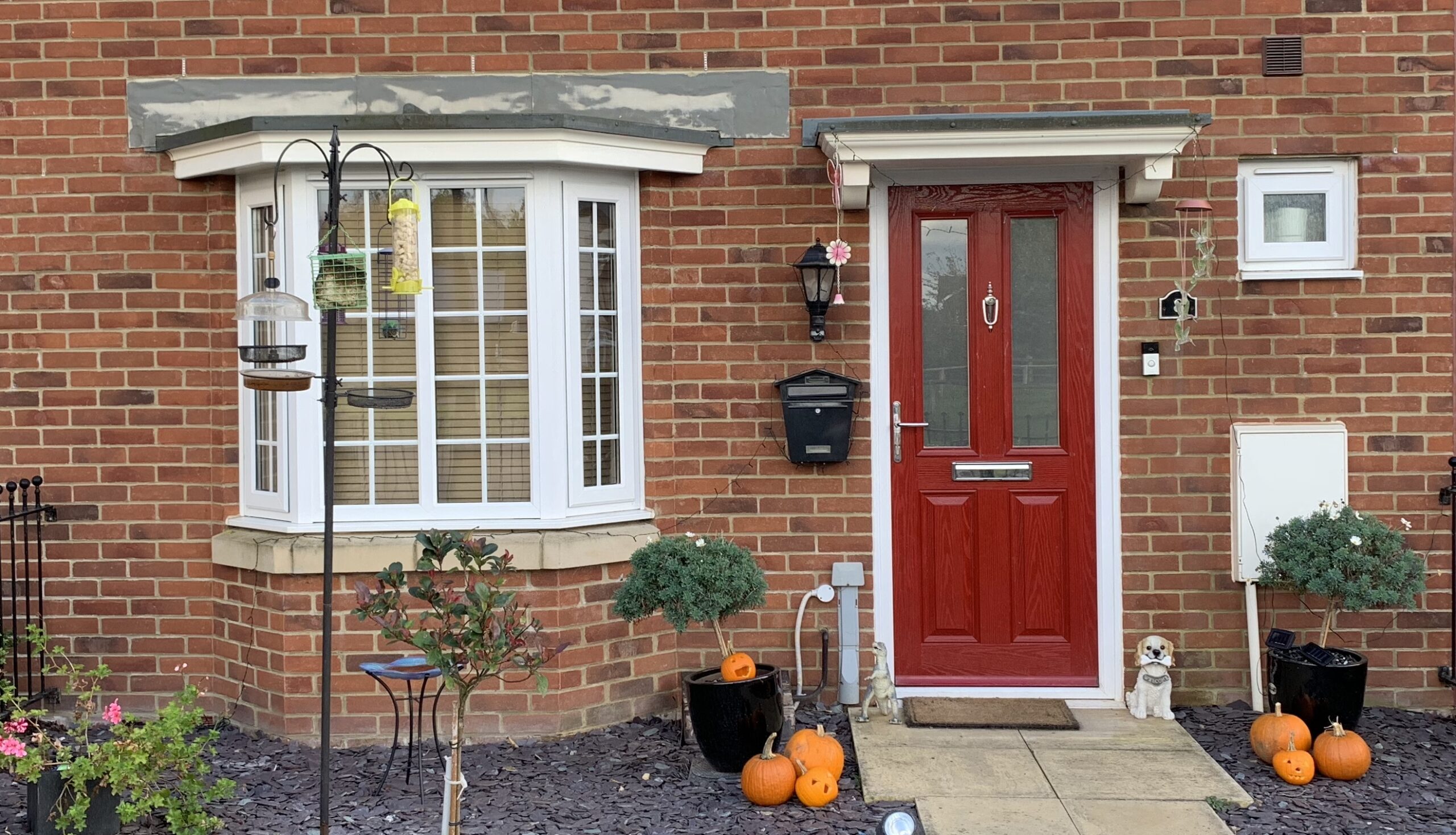 white liniar PVCu bay window beside red door, Halloween themed